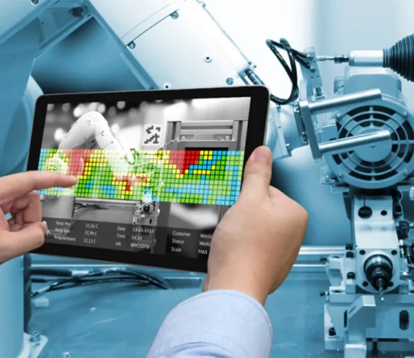 Technologie de maintenance prédictive : un technicien utilise une tablette pour analyser en temps réel les performances d’un bras robotisé connecté à l’IoT.