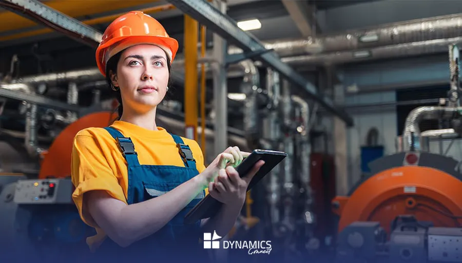 Technicienne de maintenance portant un casque orange et utilisant une tablette dans une usine, illustrant l’optimisation des interventions terrain avec Dynamics 365 Field Service — Dynamics Connect."